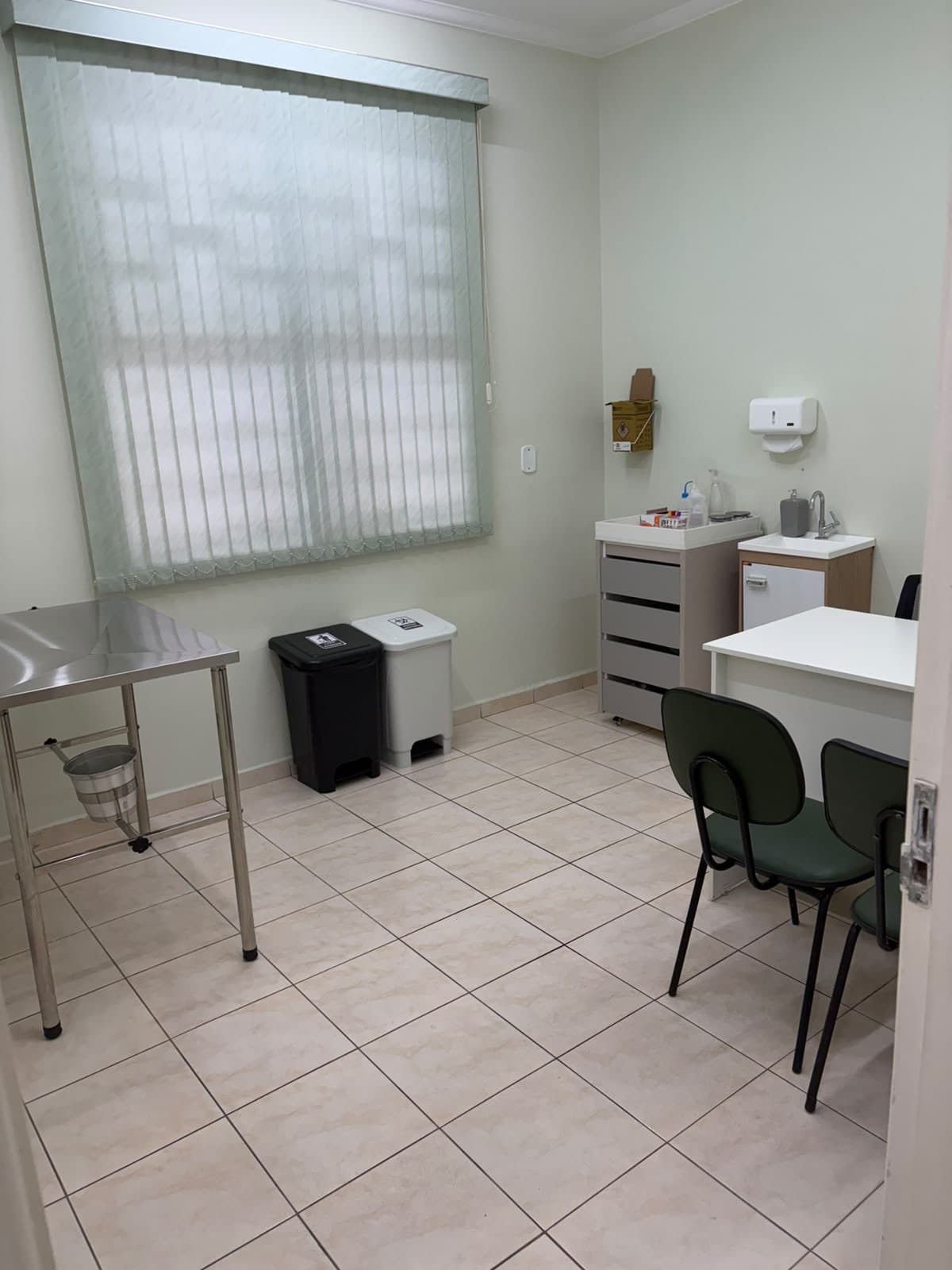 Sala de atendimento do AMA Diagnóstico Animal, com mesa inox, pia e lugares para acompanhantes